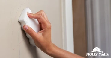 person scrubbing wall with magic eraser