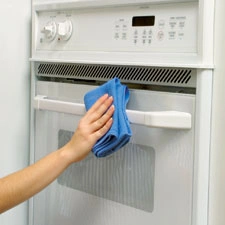 person cleaning stove with rag 