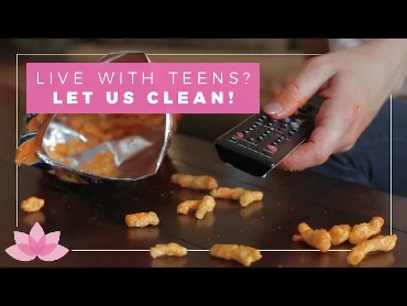 A teenager's hand with cheese residue on his fingers holding a TV remote over cheese puffs spilled on a coffee table