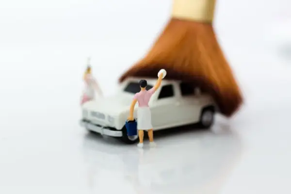 Miniature people around a small toy car