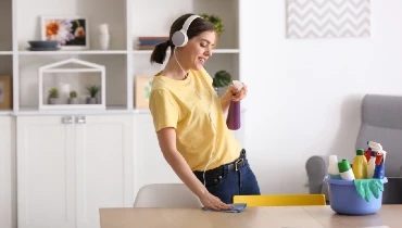 Young woman wearing headphones while cleaning table