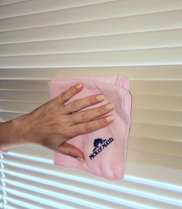 Person wiping down blinds with a Molly Maid branded cloth