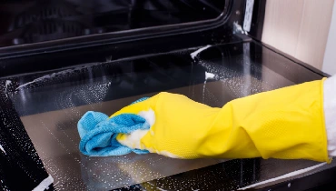 Person cleaning the glass inside oven door.