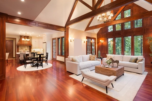 A grand living-dining area of a home with vaulted ceilings, wood beams, and rich hardwood floors throughout.