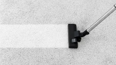 Vacuum removing dirt on a white carpet