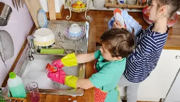 Two young children doing dishes in the kitchen