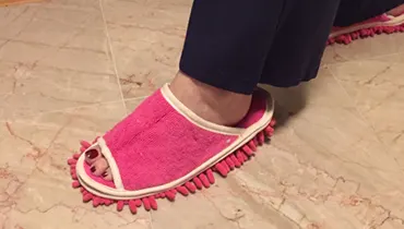 A woman's foot in a pink slipper with short mop tassels protruding from the bottom