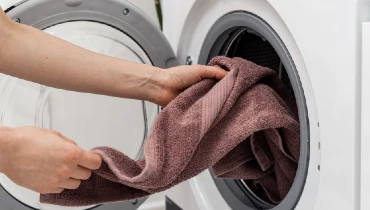 Person removing a brown colored towel from a washing machine