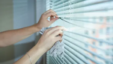 Woman cleaning blinds with a cloth