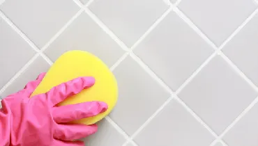 Hand in a glove cleaning the bathroom tiles