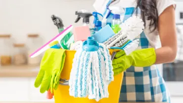 Woman holding bucket full of house cleaning supplies