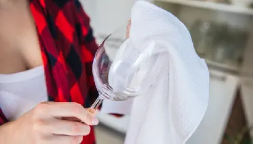 Woman cleaning a wine glass with white cloth