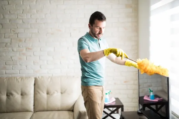 Man dusting his living room furniture.