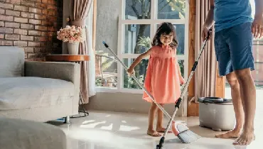 Father and daughter cleaning living room floor together