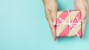 Hands holding craft paper gift box.