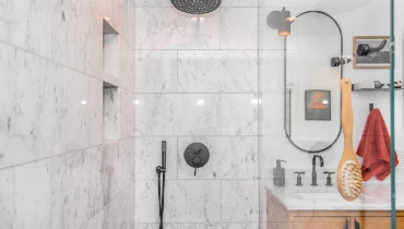 A bright, clean, modern shower with marble tile and glass door. Photo by Zac Gudakov on Unsplash.