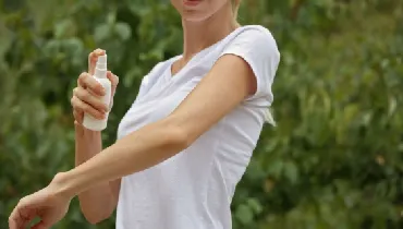 Woman using insect repellent spray outdoors