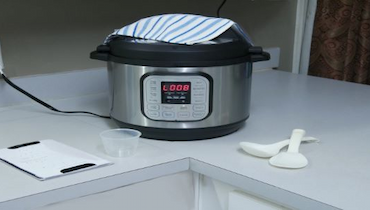 Instant pot sitting on white kitchen counter next to two white spoons.