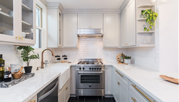 Bright, white modern kitchen with stainless steel stove.