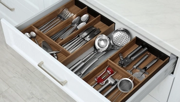 Open silverware drawer showing different utensils, cutlery and other kitchen items.