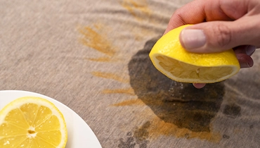 Person squeezing lemon juice onto fabric with rust stain.