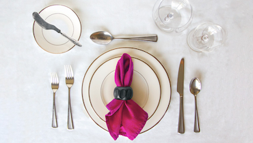 Overhead view of simple, elegant table setting with magenta cloth napkin.