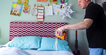 man sprinkling baking soda on child's bed.