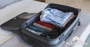 An open suitcase on a bed containing neatly folded clothes