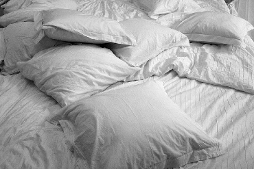 White pillows tossed on a bed with a white duvet cover. Photo cred: luc de leeuw on flickr.